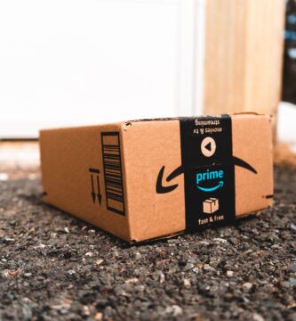 A cardboard box marked with Prime logo placed outside on a porch, ready for delivery.